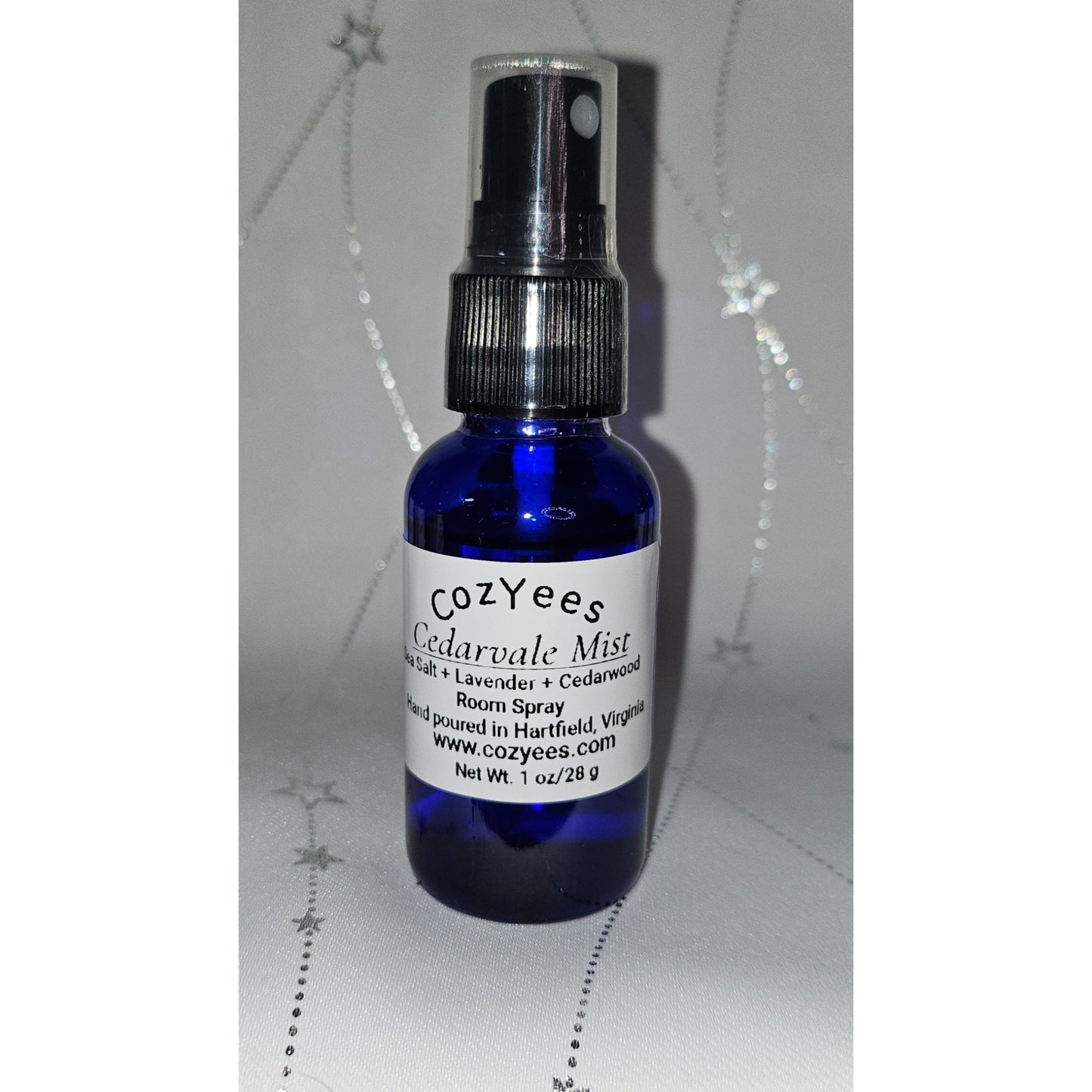 Blue spray bottle labeled 'Cozyees Cedarvale Mist' on a white background