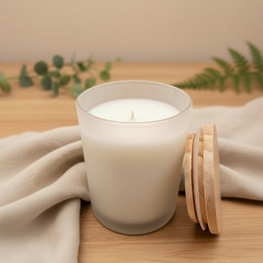 White candle in a glass jar with a wooden lid on a gray background