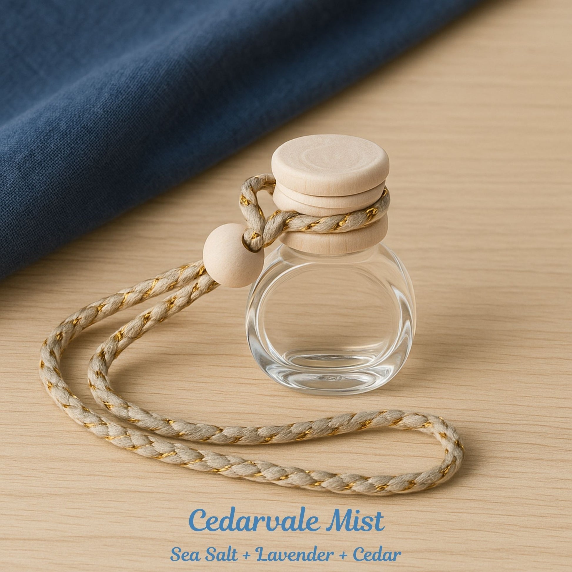 Clear glass bottle with wooden cap and rope on a wooden surface, labeled 'Cedarvale Mist'.