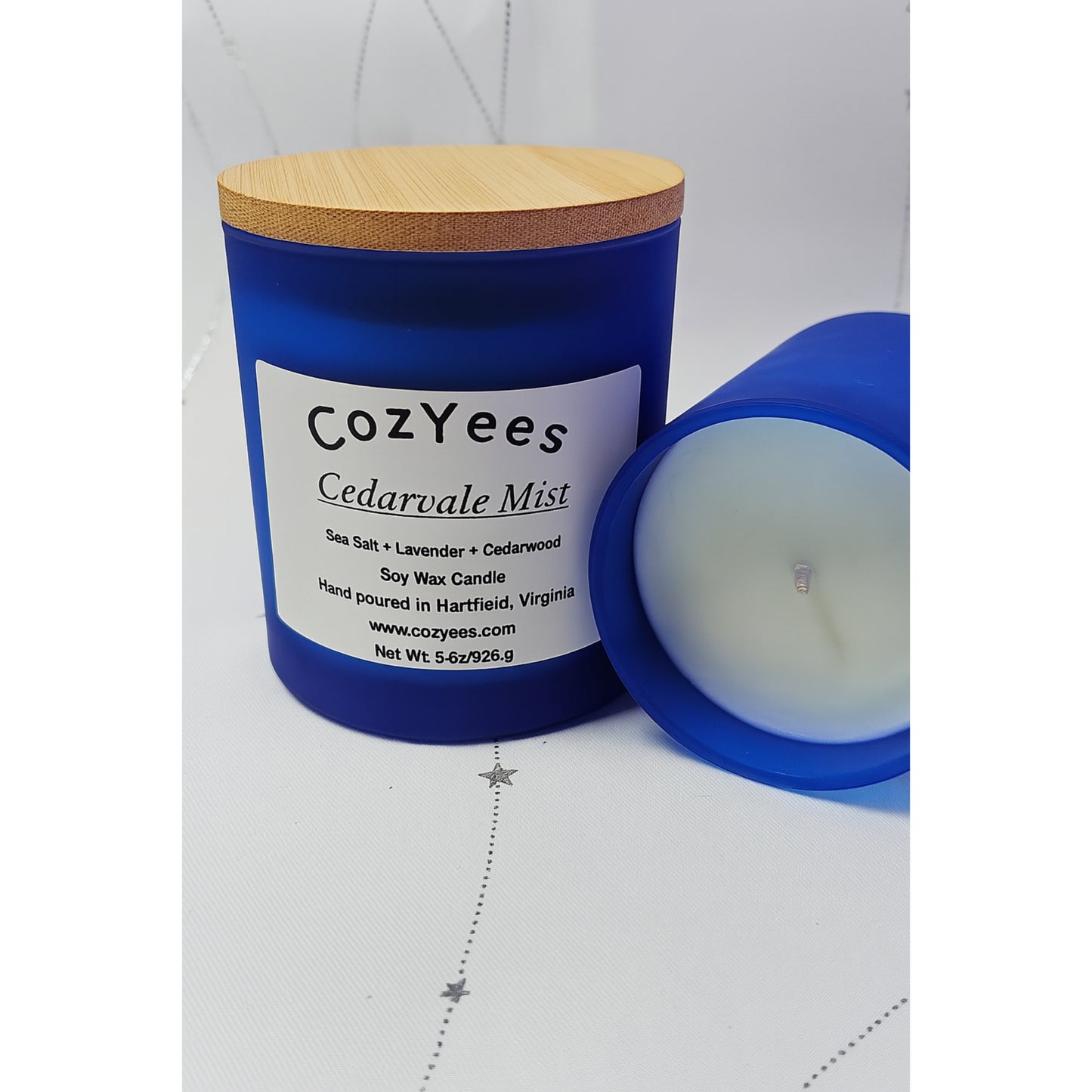 CozYees Cedarale Mist candle with blue container and wooden lid on a white background