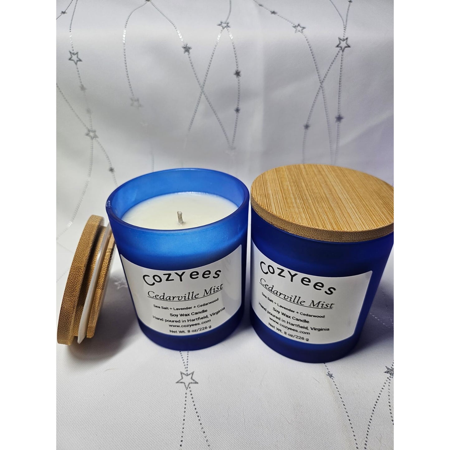Cozyees Cedarville Mist candle with blue container and wooden lid on a white background