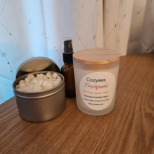 Cozyees Fruitquake candle and a small container with white beads on a wooden surface.