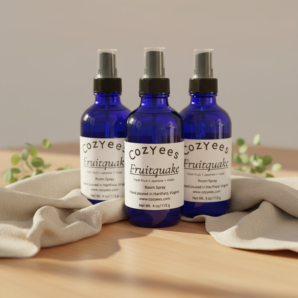 Three Cozyees Fruitquake room spray bottles on a white surface.