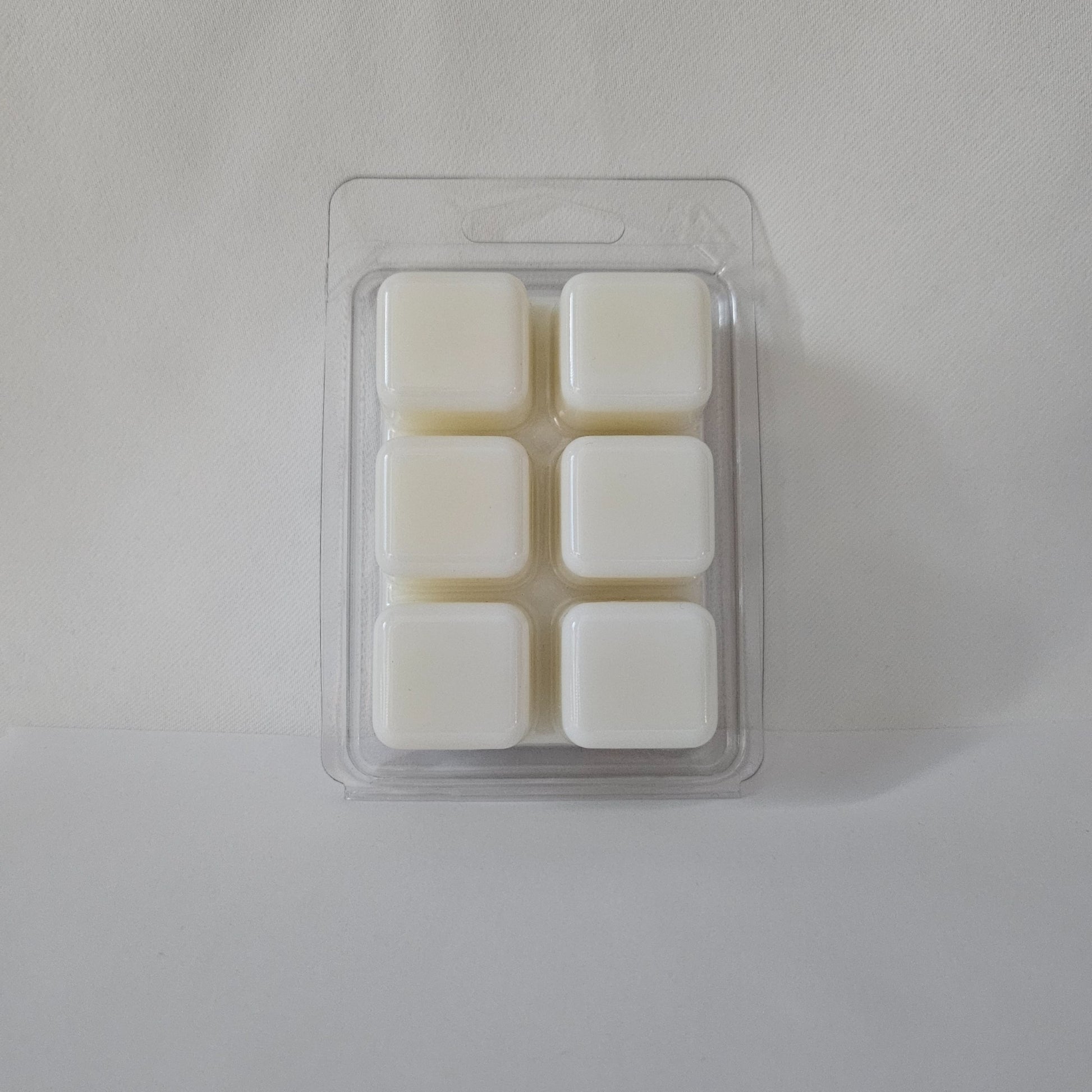 Pack of four white wax melts in a clear plastic packaging on a light gray background