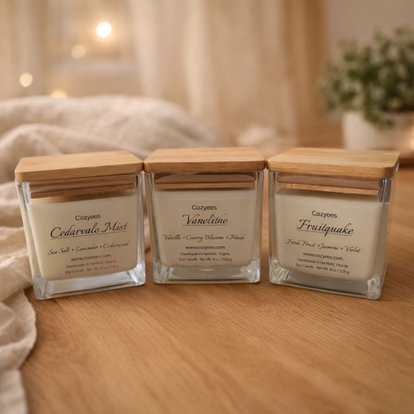 Three Cozyees candles with wooden lids on a wooden surface.