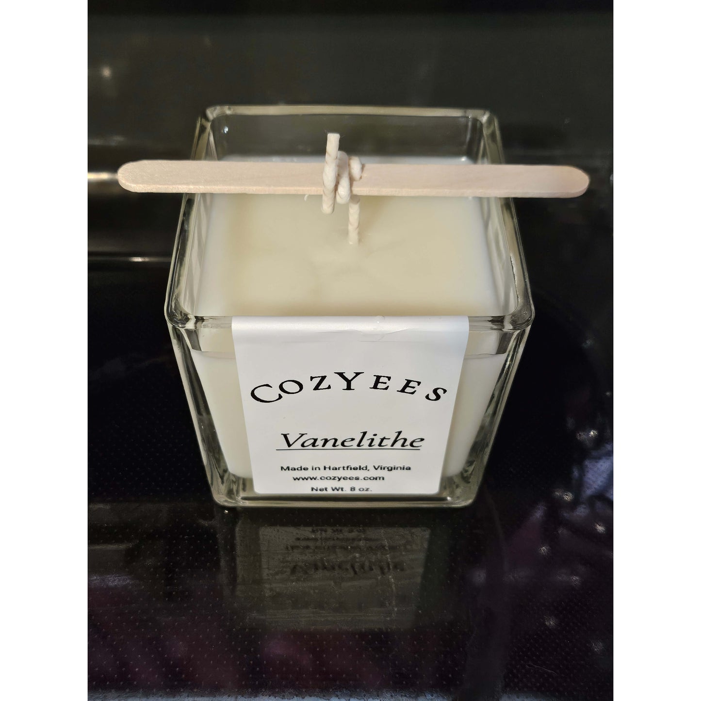 Cozyees candle with a label on a dark background