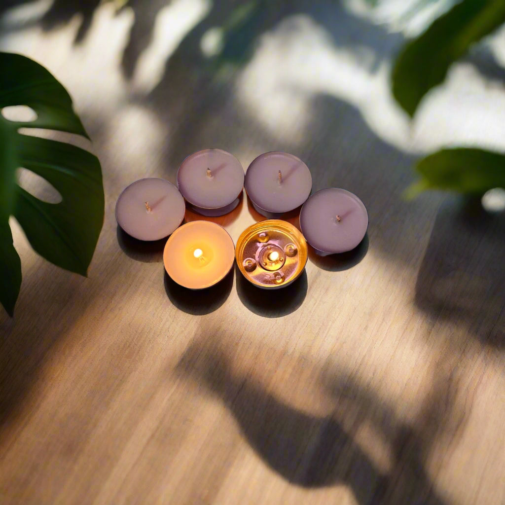 Three lit candles on a purple fabric background with star patterns