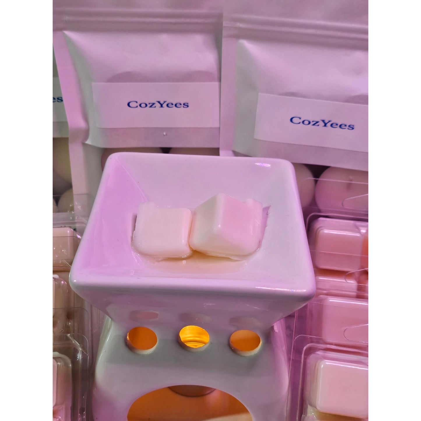 White wax melts in a CozYees warmer with multiple CozYees packages in the background.