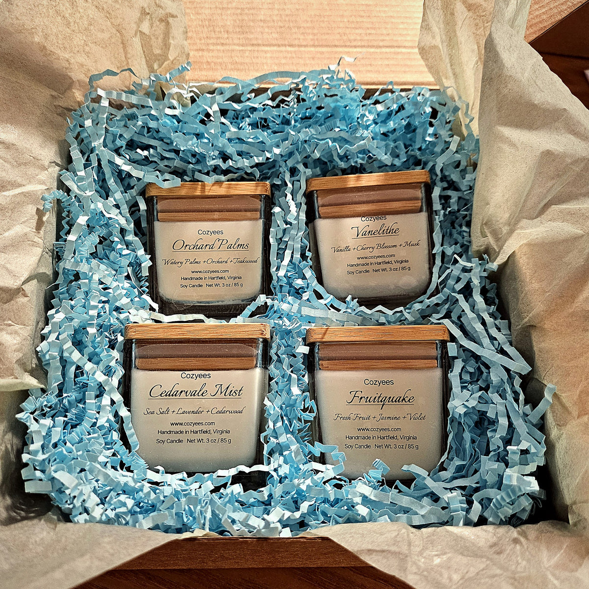 Cozyees sampler gift set of four 3 oz soy candles with bamboo lids in a gift box with blue crinkle paper