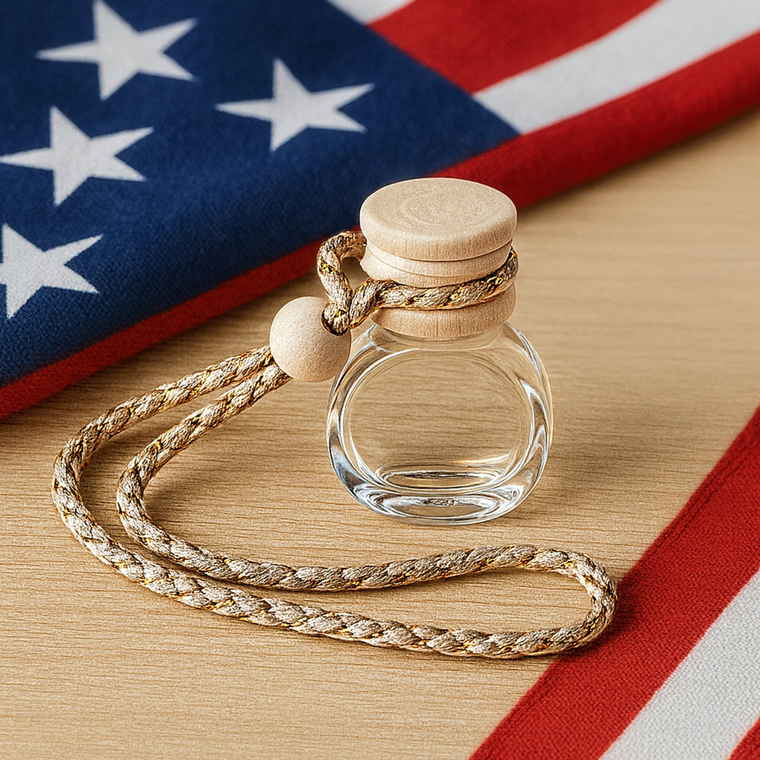 Cozyees car freshener in glass bottle with woord cap on a wood table with an American Flag