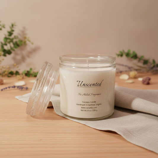 Cozyees unscented candle in a clear glass on a wood table.