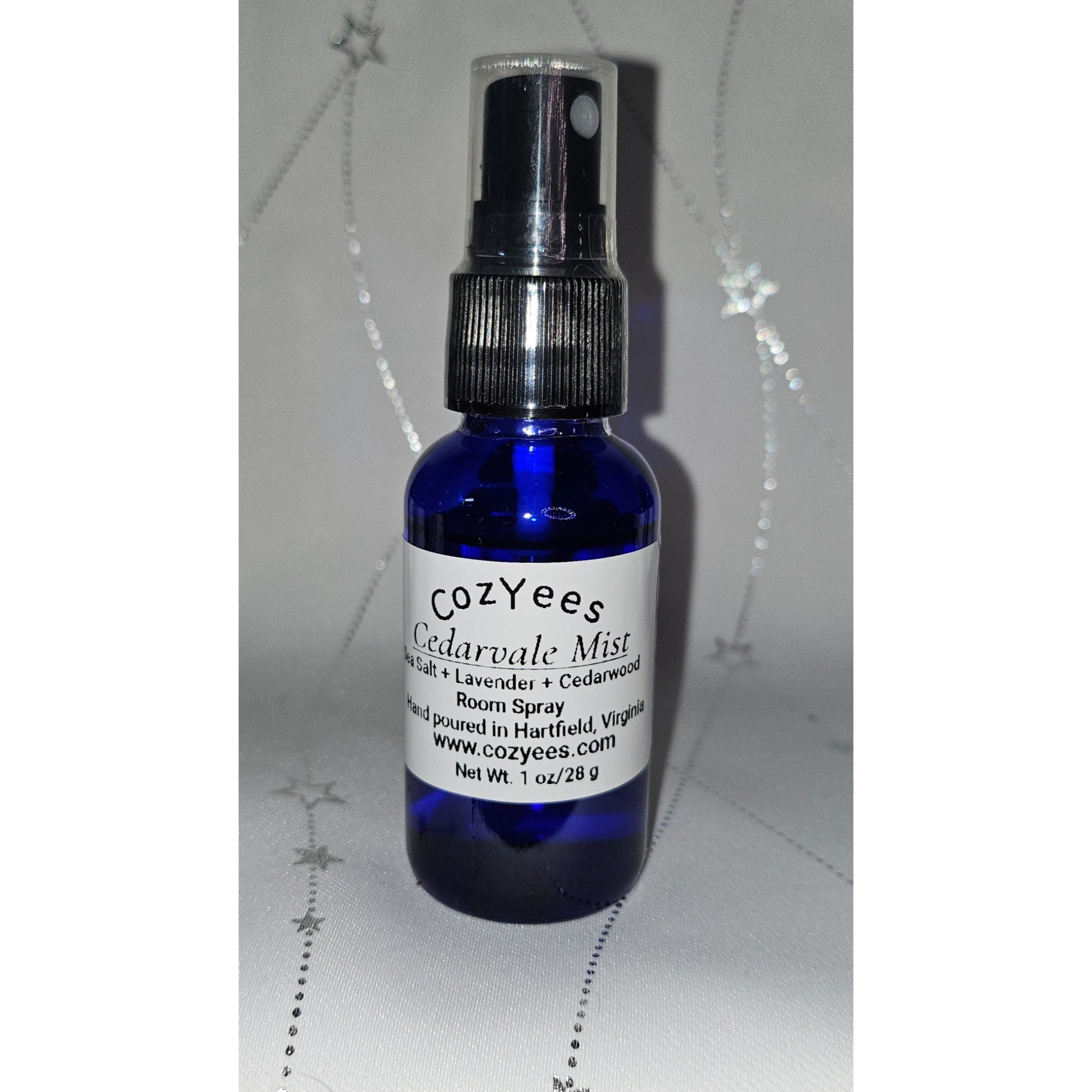 Blue spray bottle labeled 'Cozyees Cedarvale Mist' on a white background
