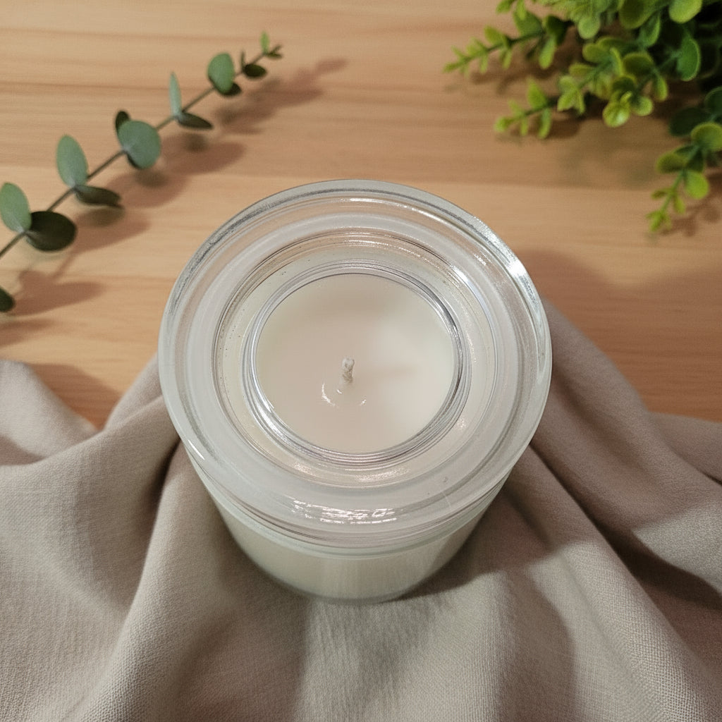 Clear glass candle holder with a white candle on a white background