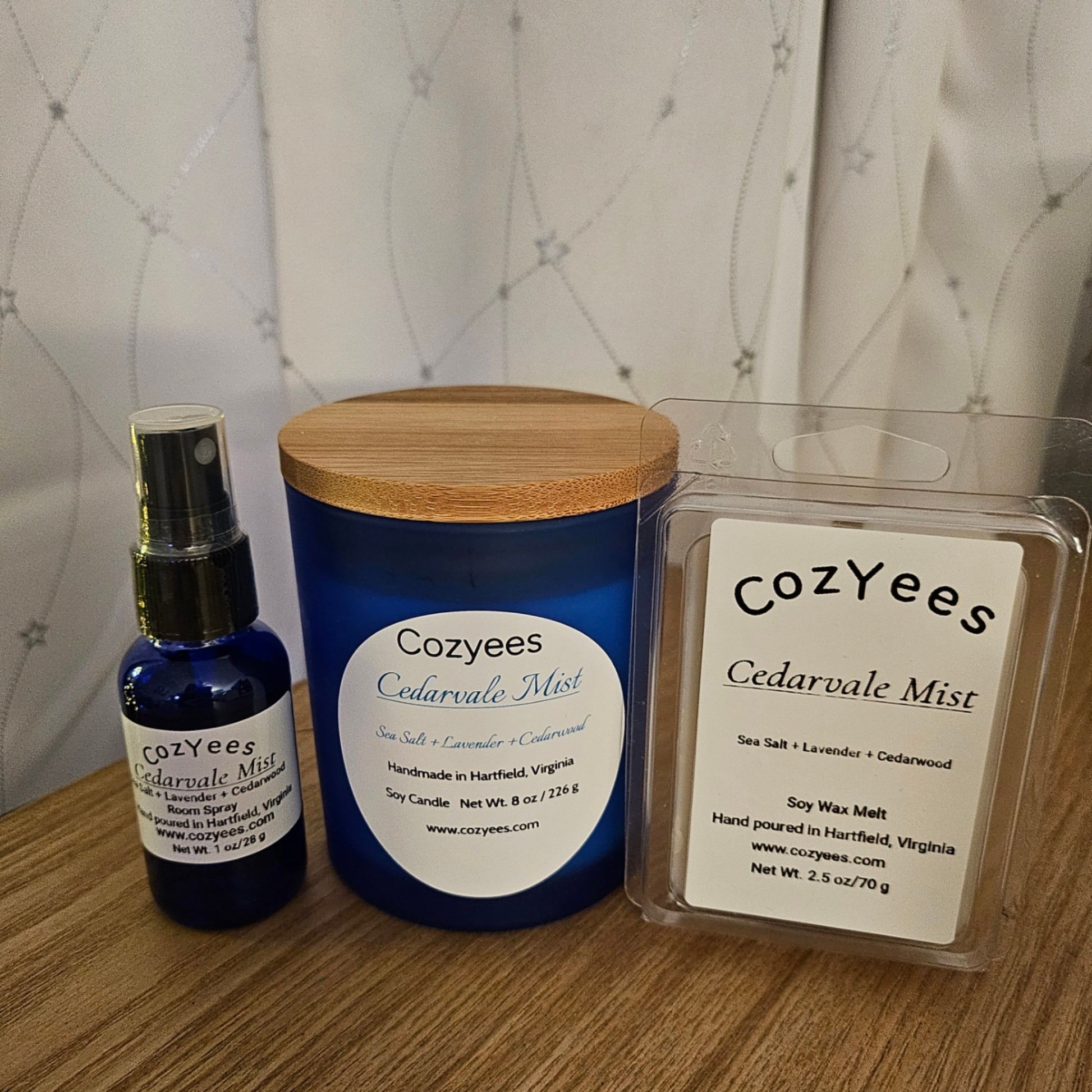 Cozyees Cedarvale Mist products including a bottle, candle, and wax melt on a wooden surface.