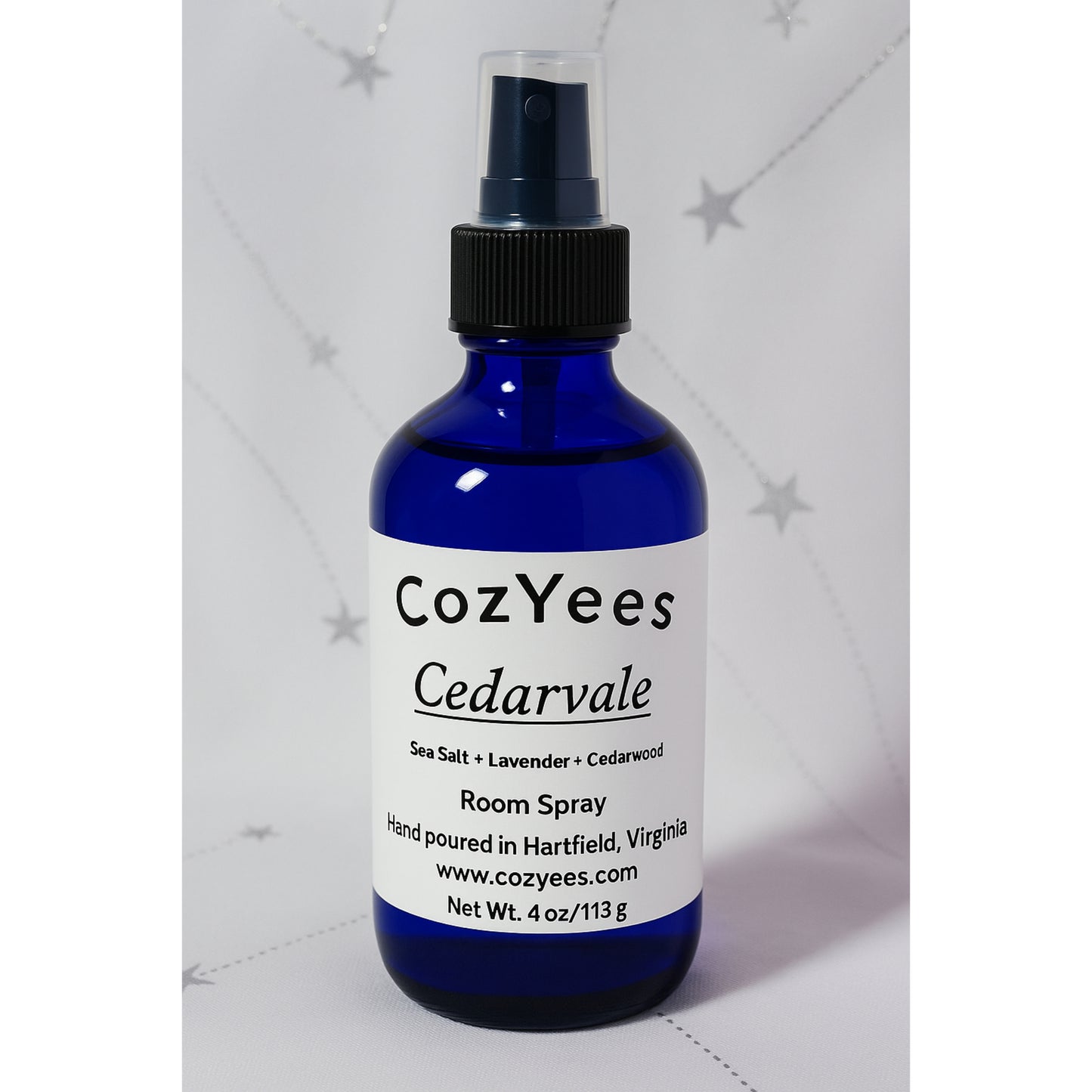 Blue spray bottle labeled 'CozYees Cedarvale' on a light gray background