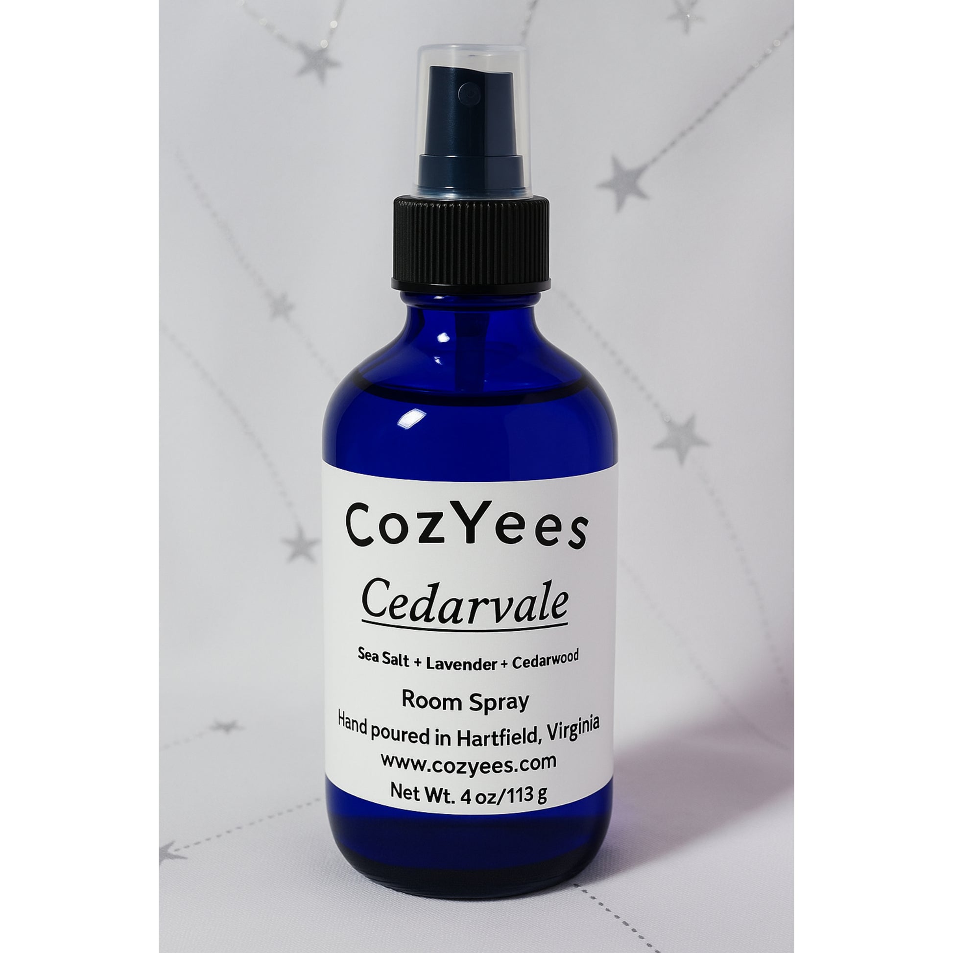 Blue spray bottle labeled 'CozYees Cedarvale' on a light gray background