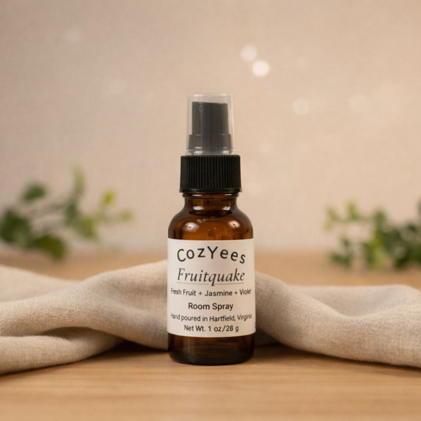 Cozyees Fruitquake room spray bottle on a wooden surface with a soft background