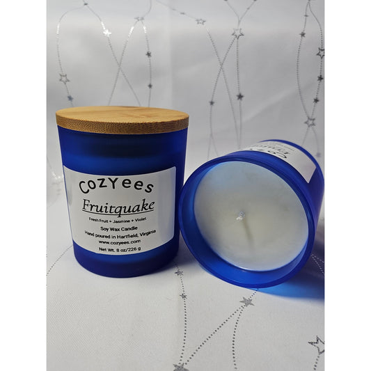 Blue candle with wooden lid and white label on a white background