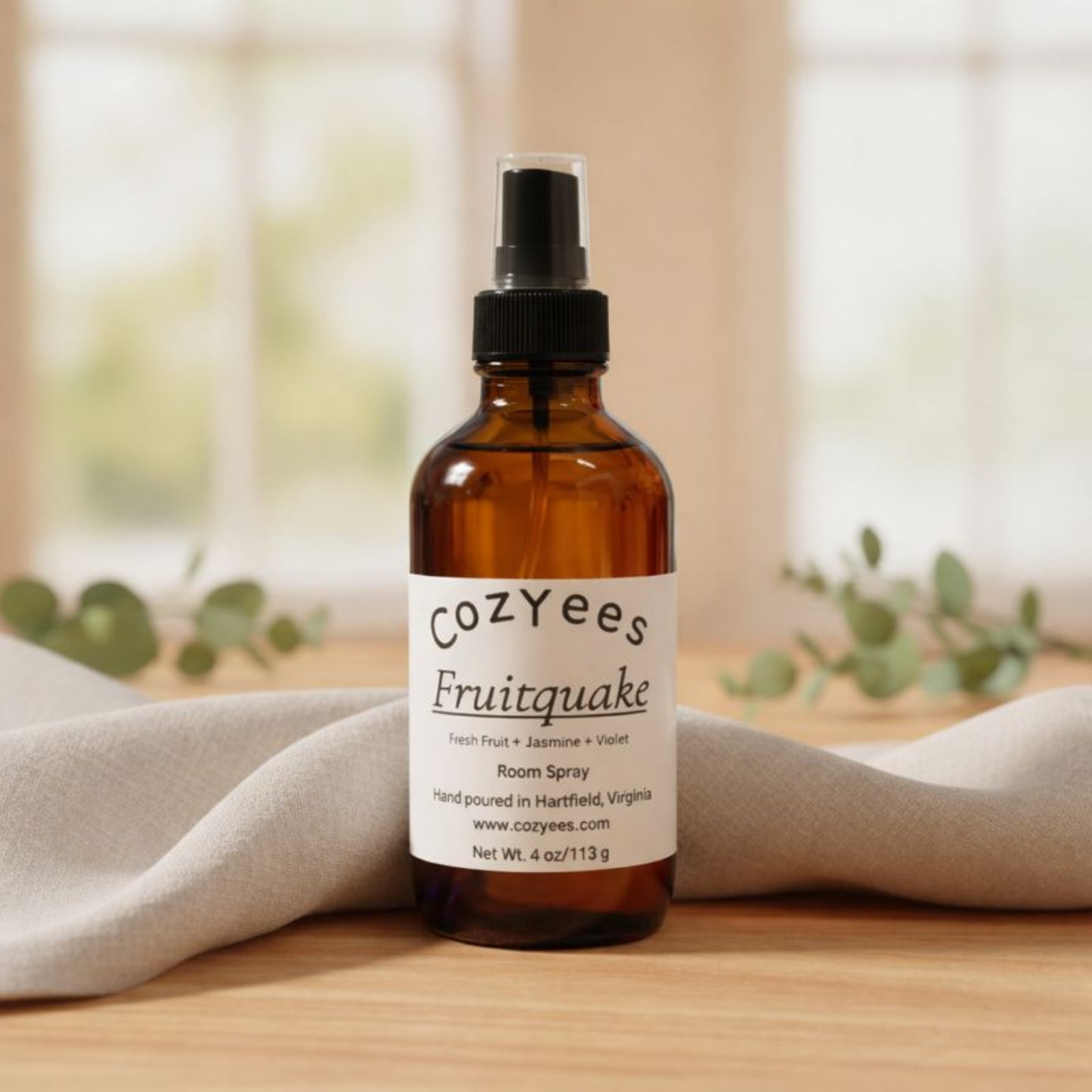 CoZYees Fruitquake room spray bottle on a wooden surface with a blurred natural background