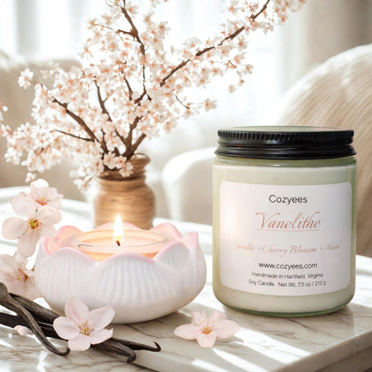 Cozyees Vanelithe candle with cherry blossoms and vanilla beans on a marble surface