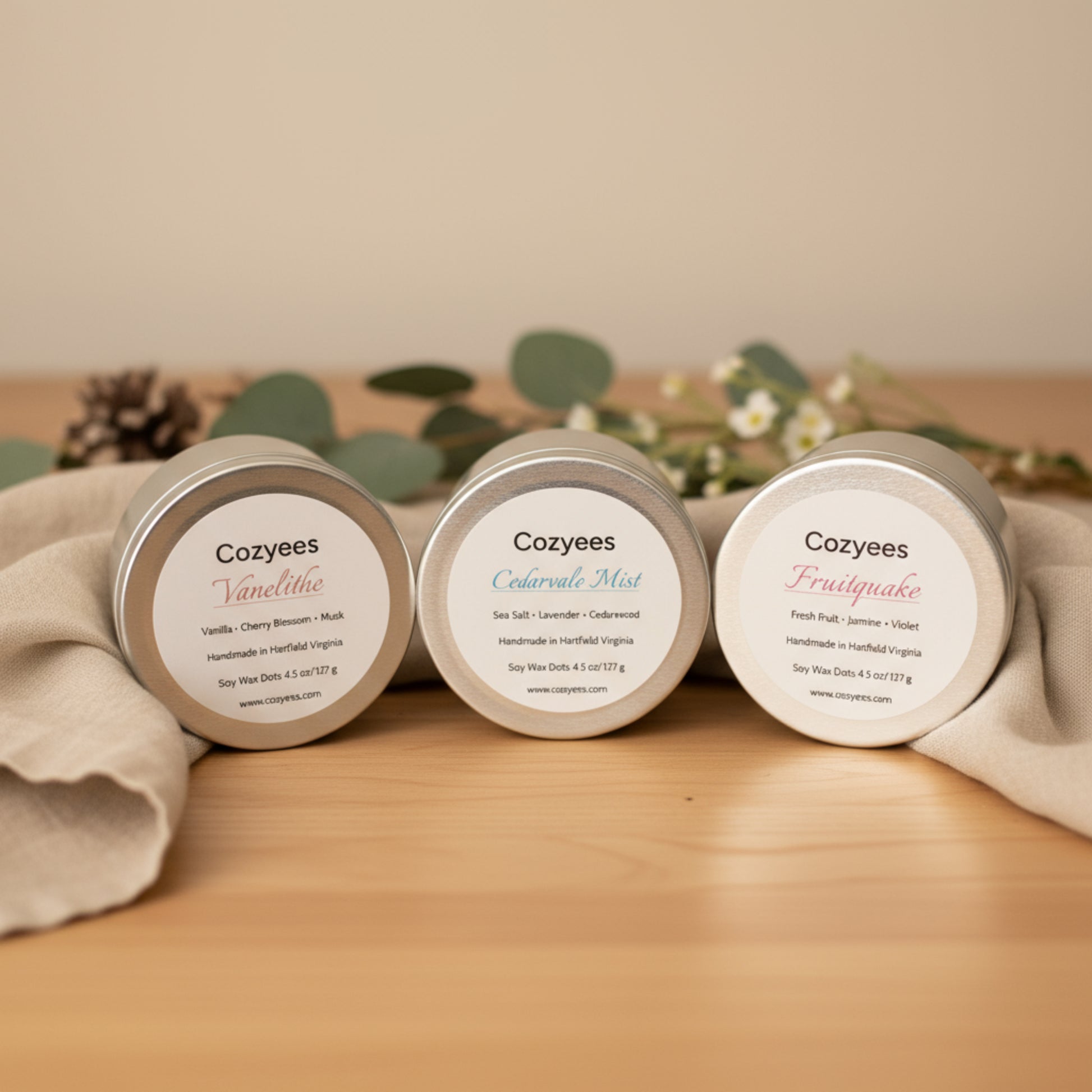 Three Cozyees candles on a wooden surface with a neutral background