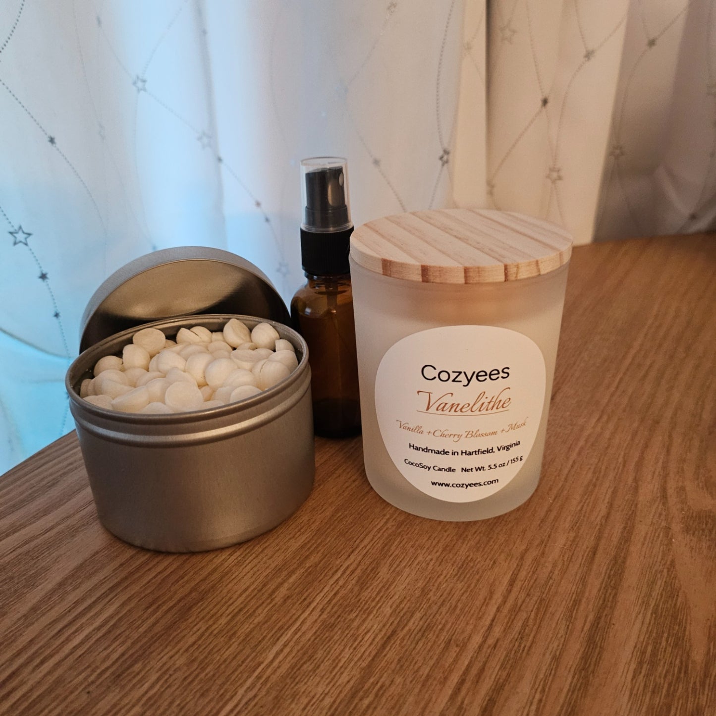 Candle, small container with white balls, and bottle on a wooden surface