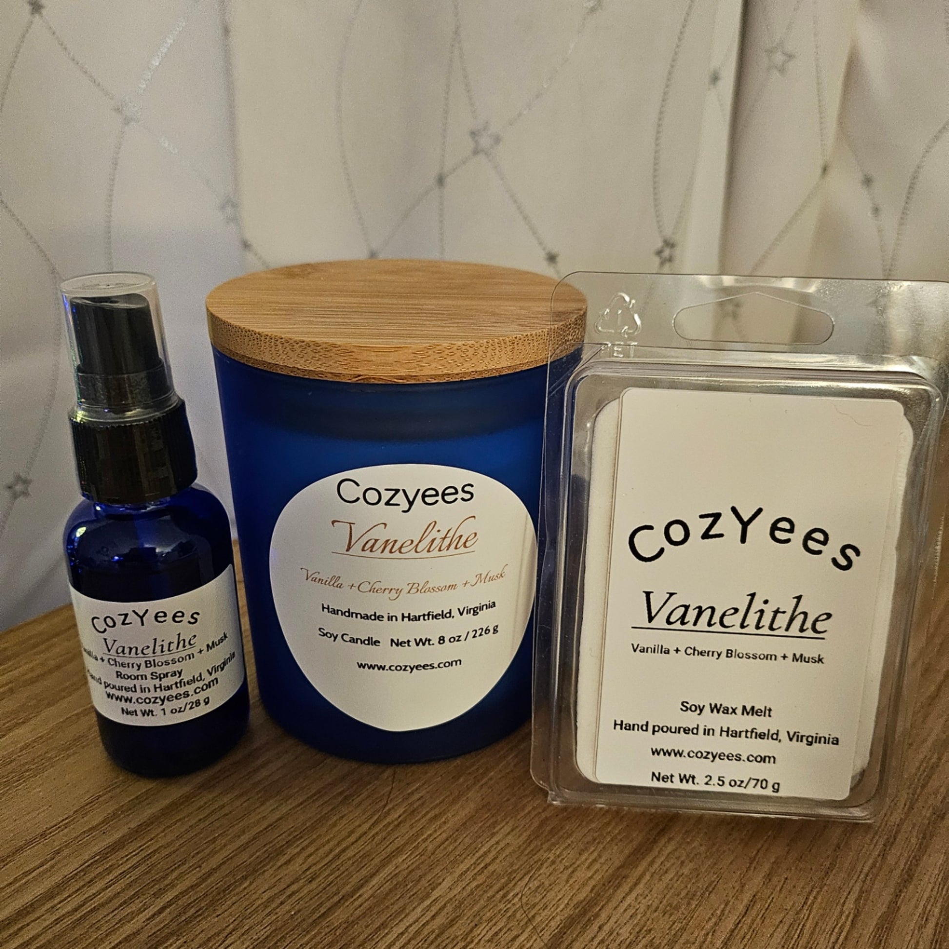 Cozyees Vanelithe candle, spray bottle, and wax melt on a wooden surface with a neutral background.