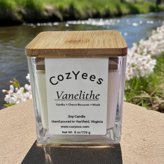 Cozyees Vanelithe candle with wooden lid outdoors by a body of water