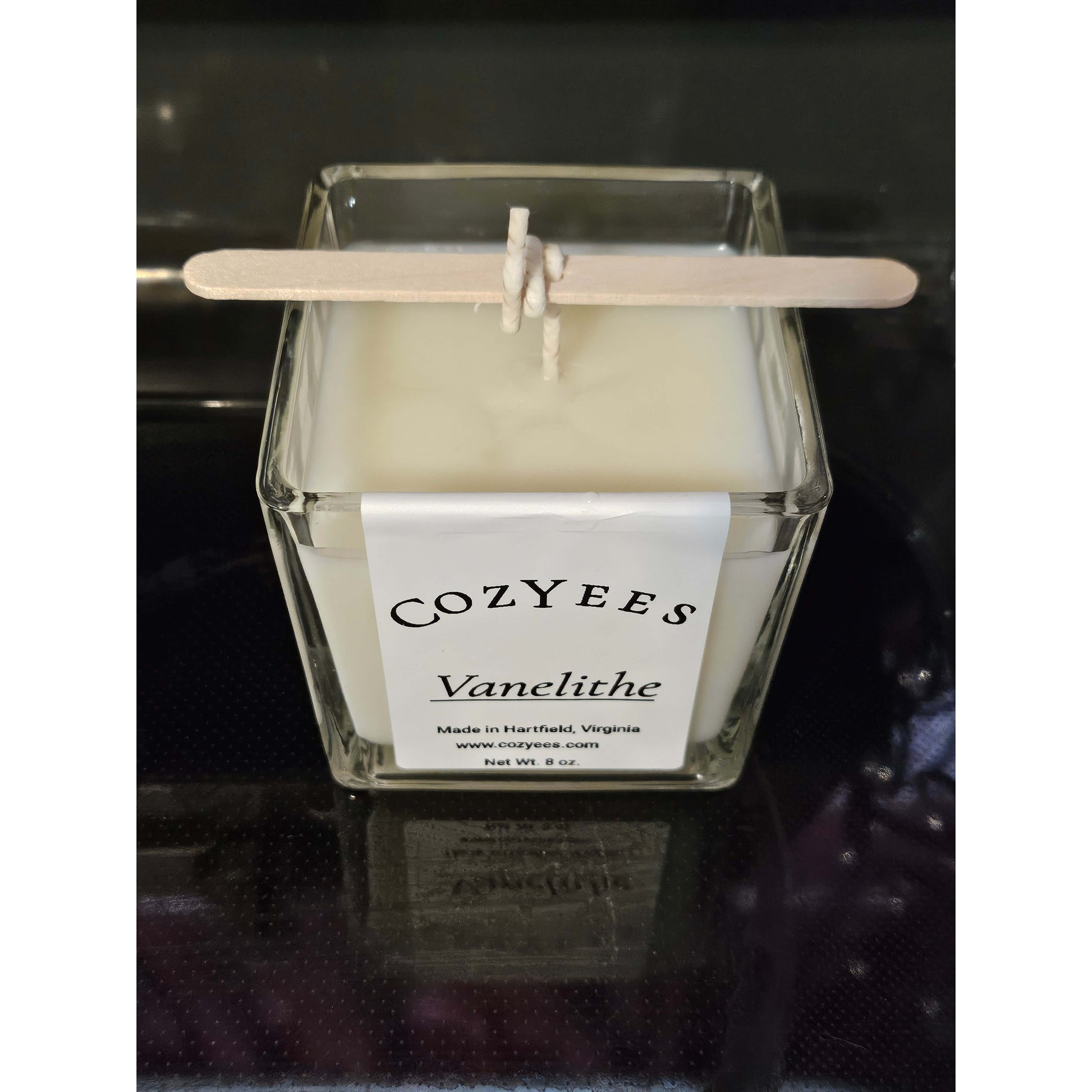 Cozyees candle with a label on a dark background