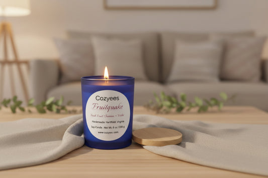 Cozyees blue jar with lit canlde on a wood table in fornt of sofa.