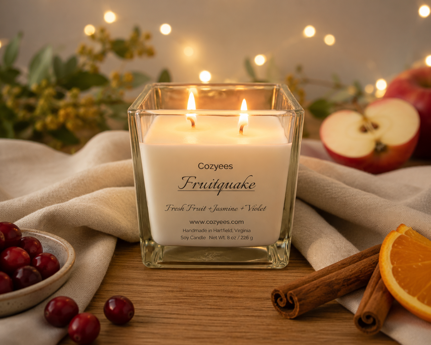 cozyees fruitquake soy candle in a square jar lit on a table