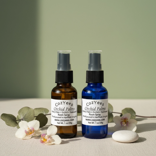 Two cozYee Orchid Palms room spray bottles with flowers and a stone on a light surface.